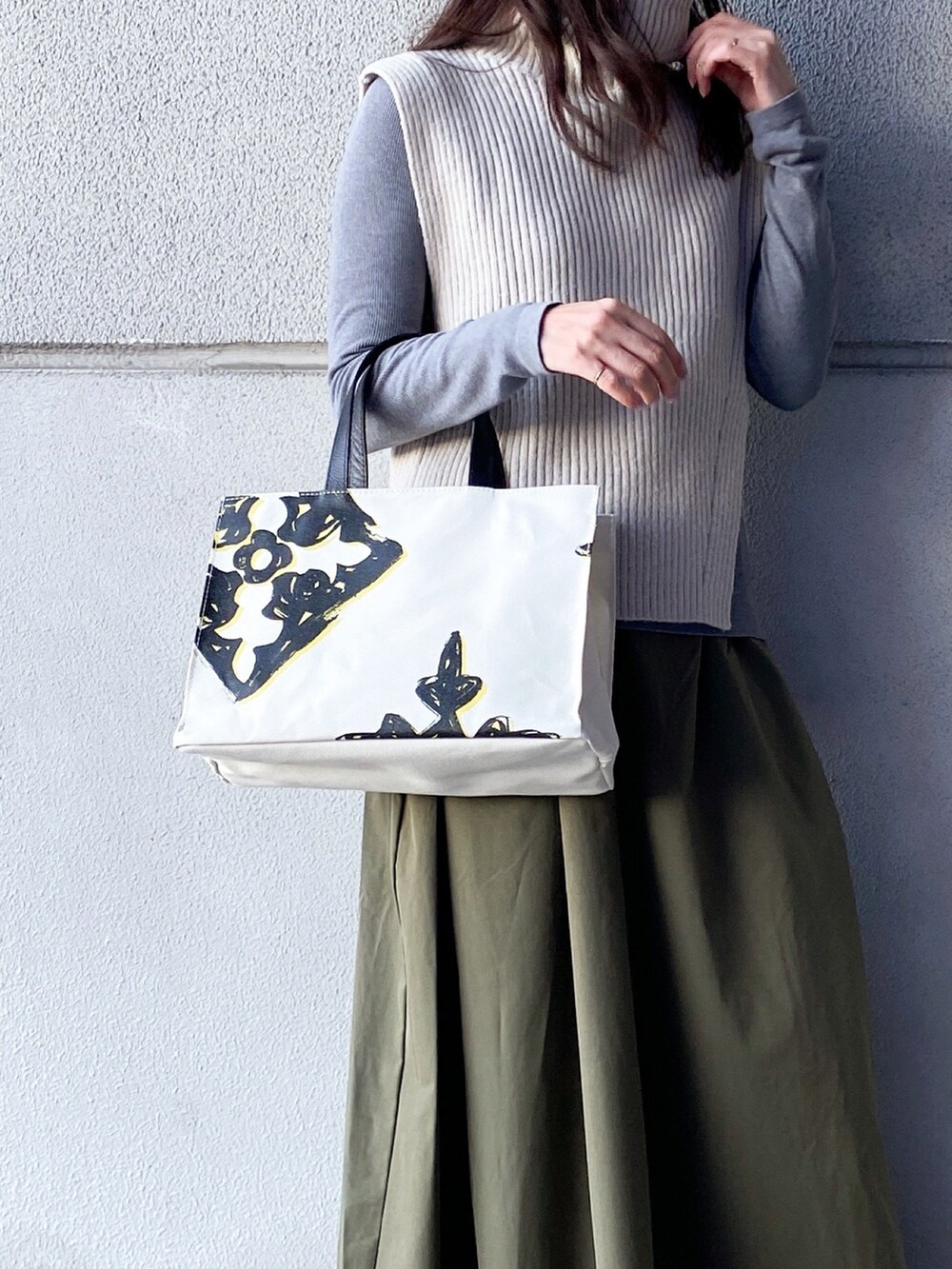 ホワイト系のトートバッグ、ホワイト系のベスト、グレー系のTシャツ/カットソーを着用したレディースの冬コーディネートの3枚目の写真