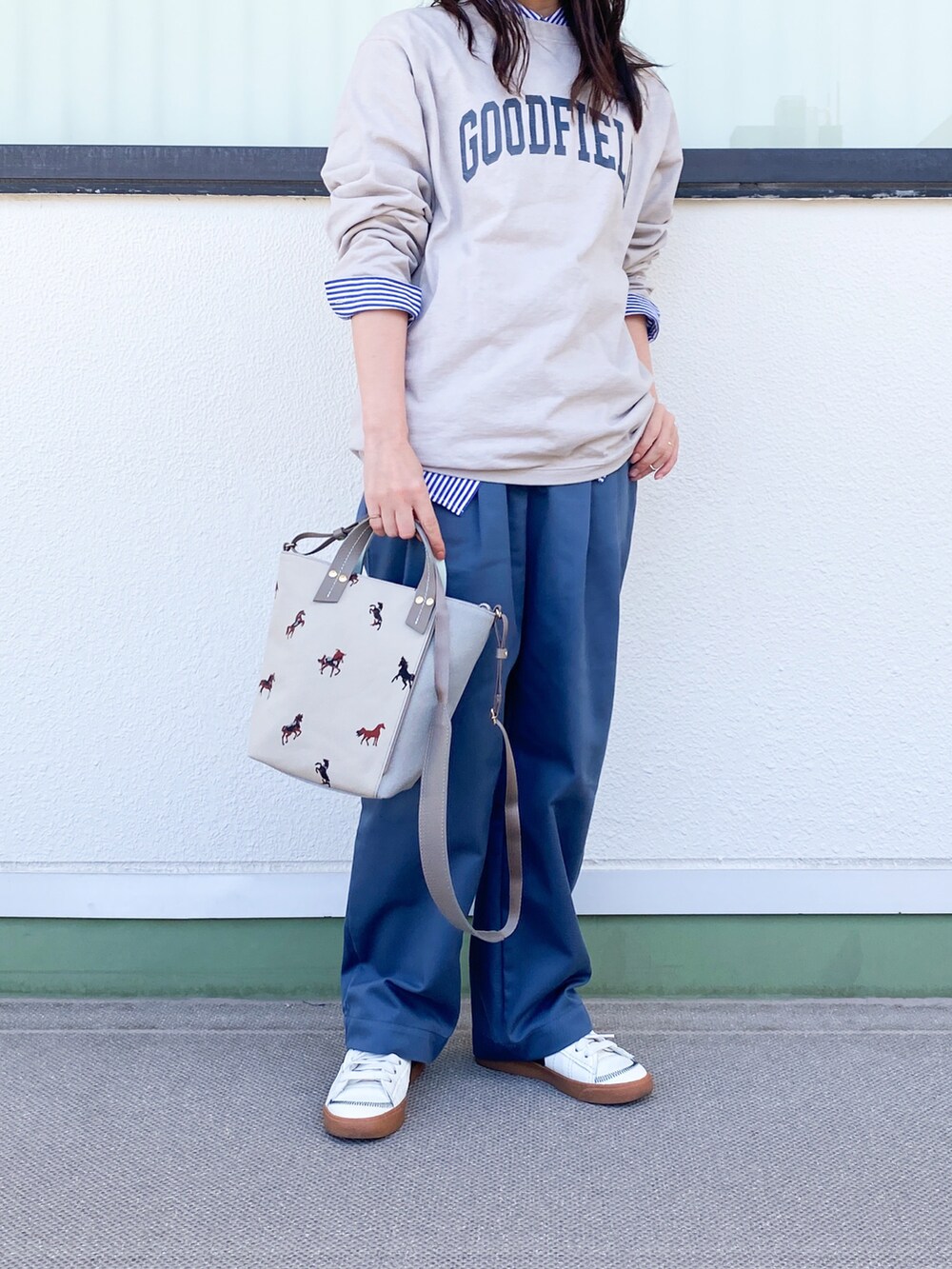 グレー系のショルダーバッグ、ブルー系のスラックス、ホワイト系のスニーカーを着用したレディースの春コーディネートの3枚目の写真