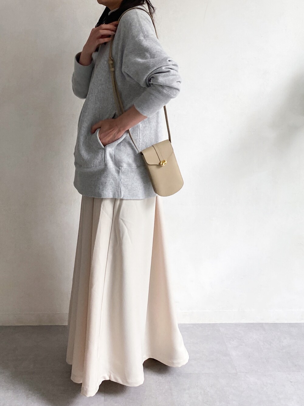 ベージュ系のショルダーバッグ、ホワイト系のスカート、ホワイト系のスニーカーを着用したレディースの冬コーディネートの4枚目の写真