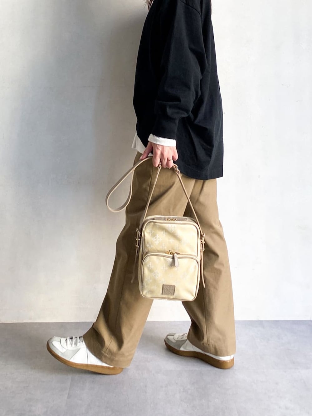 イエロー系のショルダーバッグ、ベージュ系のチノパンツ、ホワイト系のスニーカーを着用したレディースの冬コーディネートの3枚目の写真