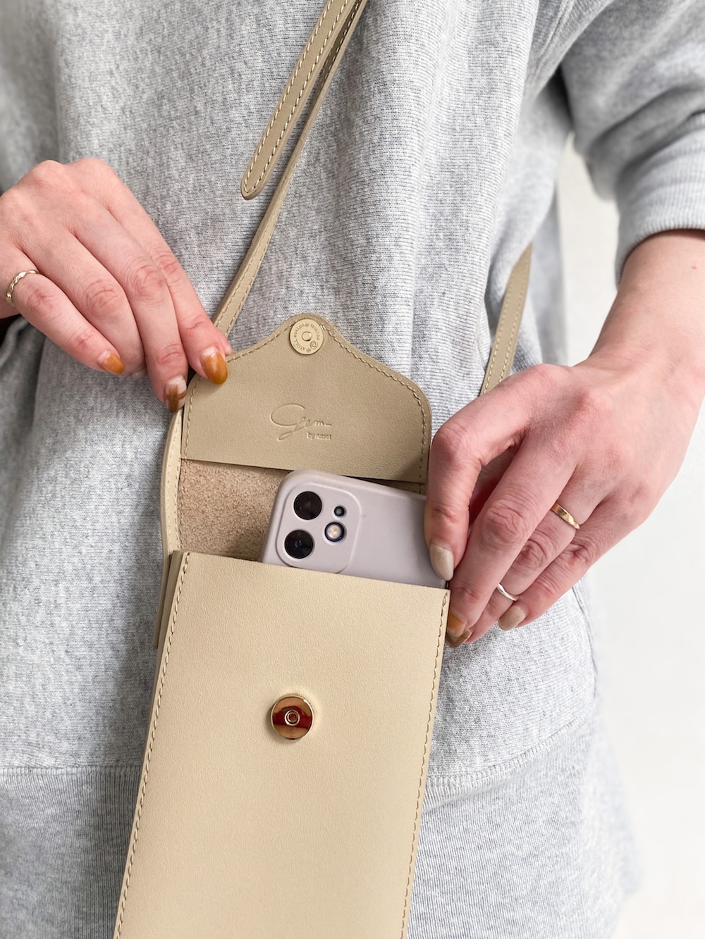 ベージュ系のショルダーバッグ、ホワイト系のスカート、ホワイト系のスニーカーを着用したレディースの冬コーディネートの5枚目の写真