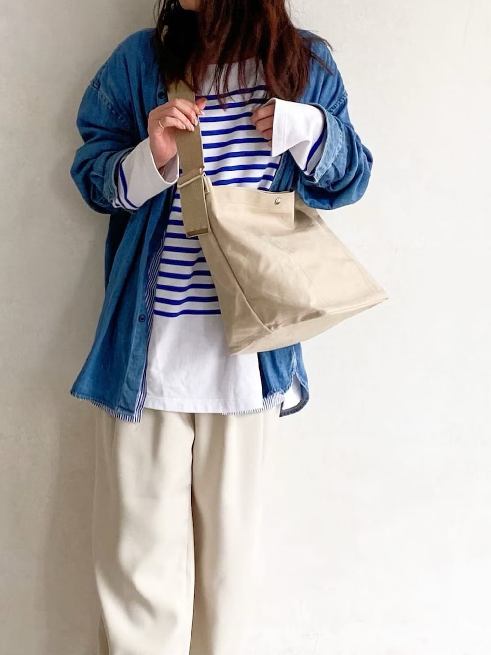 ホワイト系のショルダーバッグ、ブルー系のシャツ/ブラウス、ホワイト系のスラックスを着用したレディースの春コーディネートの2枚目の写真