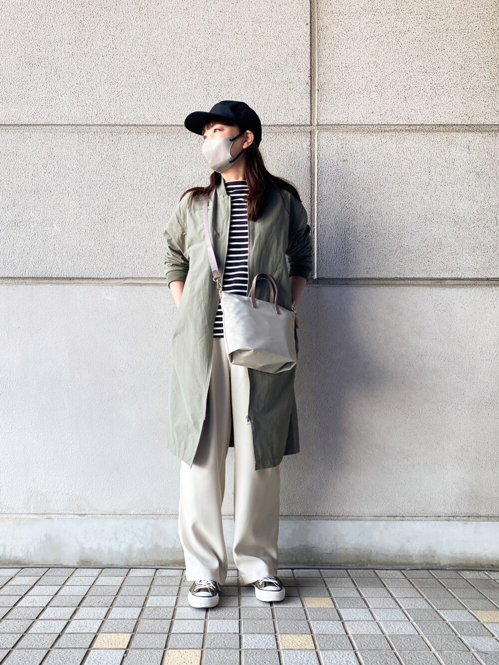 グリーン系のノーカラーコート、ブラック系のTシャツ/カットソー、ホワイト系のスラックスを着用したレディースの春コーディネートの2枚目の写真