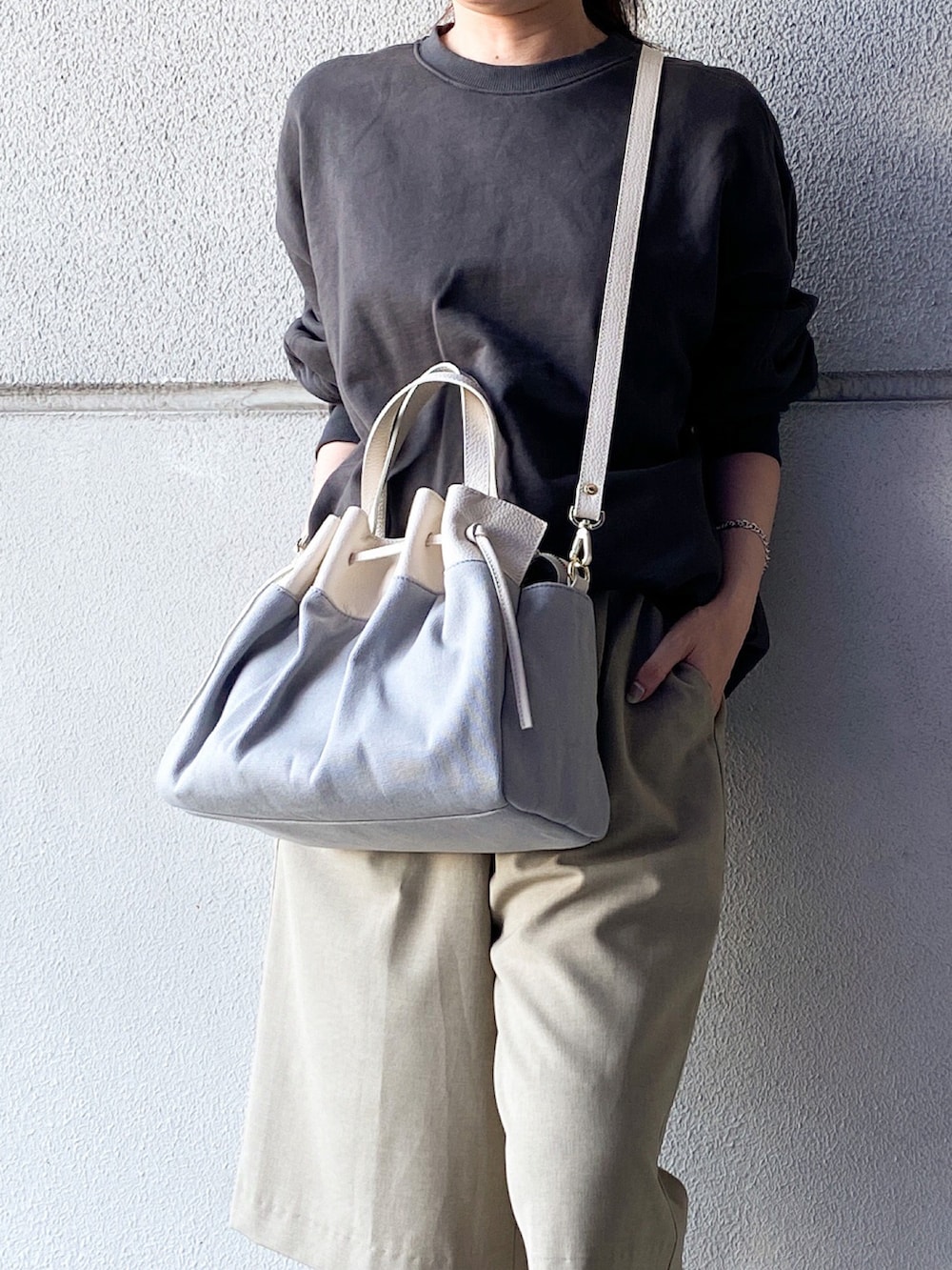 グレー系のトートバッグ、グレー系のスウェット、ベージュ系のパンツを着用したレディースの夏コーディネートの2枚目の写真