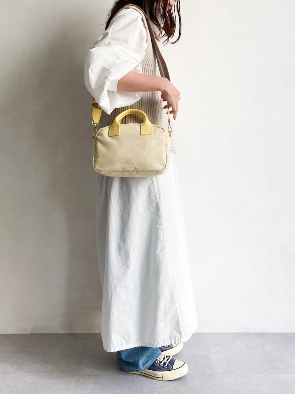 イエロー系のショルダーバッグを着用したレディースの冬コーディネートの2枚目の写真