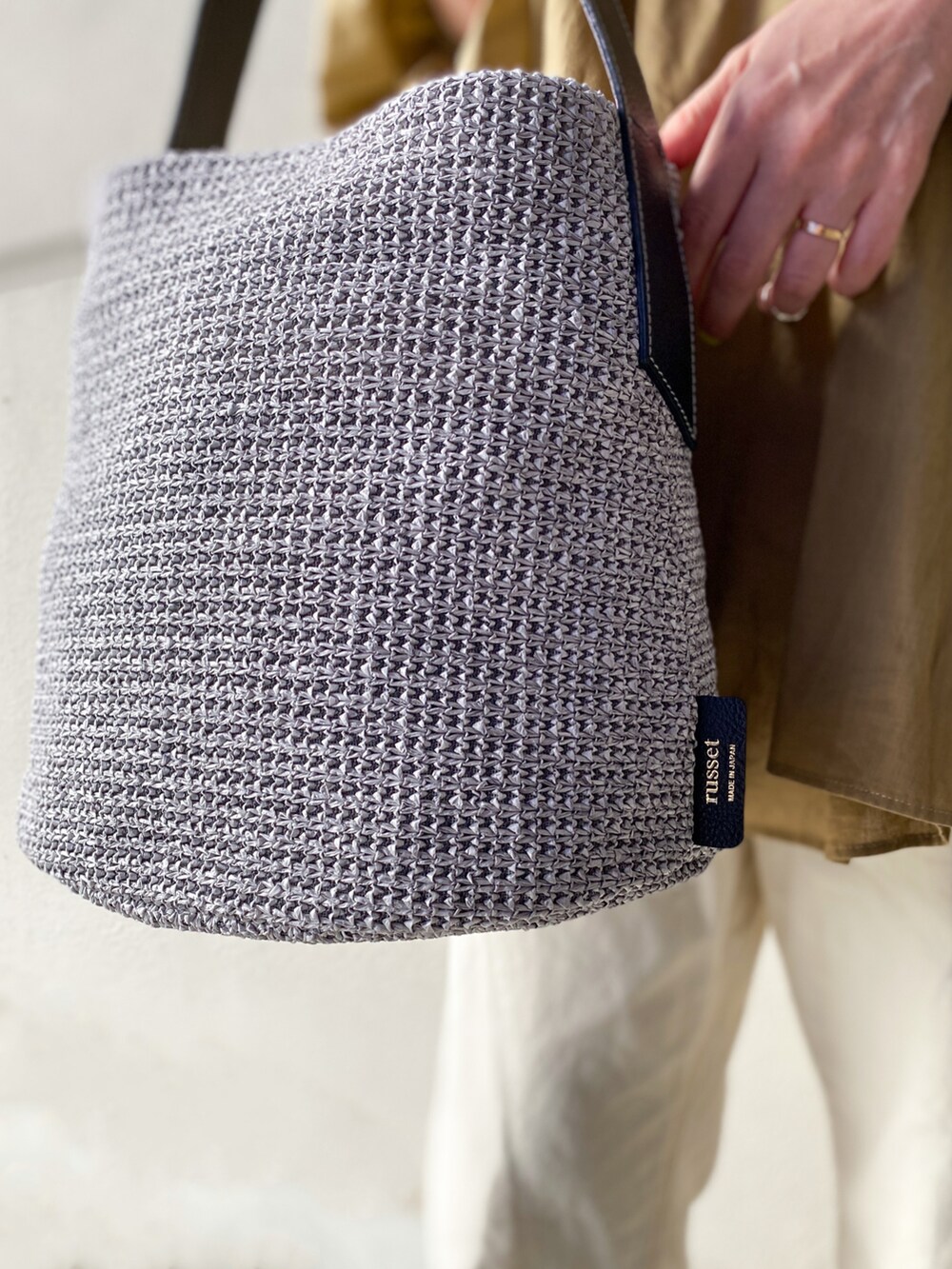 グレー系のショルダーバッグ、ベージュ系のシャツ/ブラウス、ホワイト系のデニムパンツを着用したレディースの春コーディネートの3枚目の写真