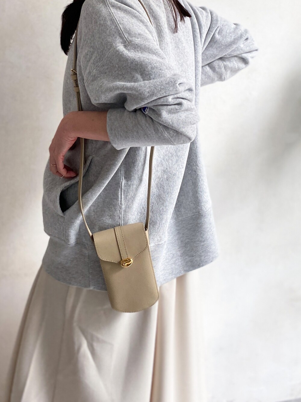 ベージュ系のショルダーバッグ、ホワイト系のスカート、ホワイト系のスニーカーを着用したレディースの冬コーディネートの3枚目の写真