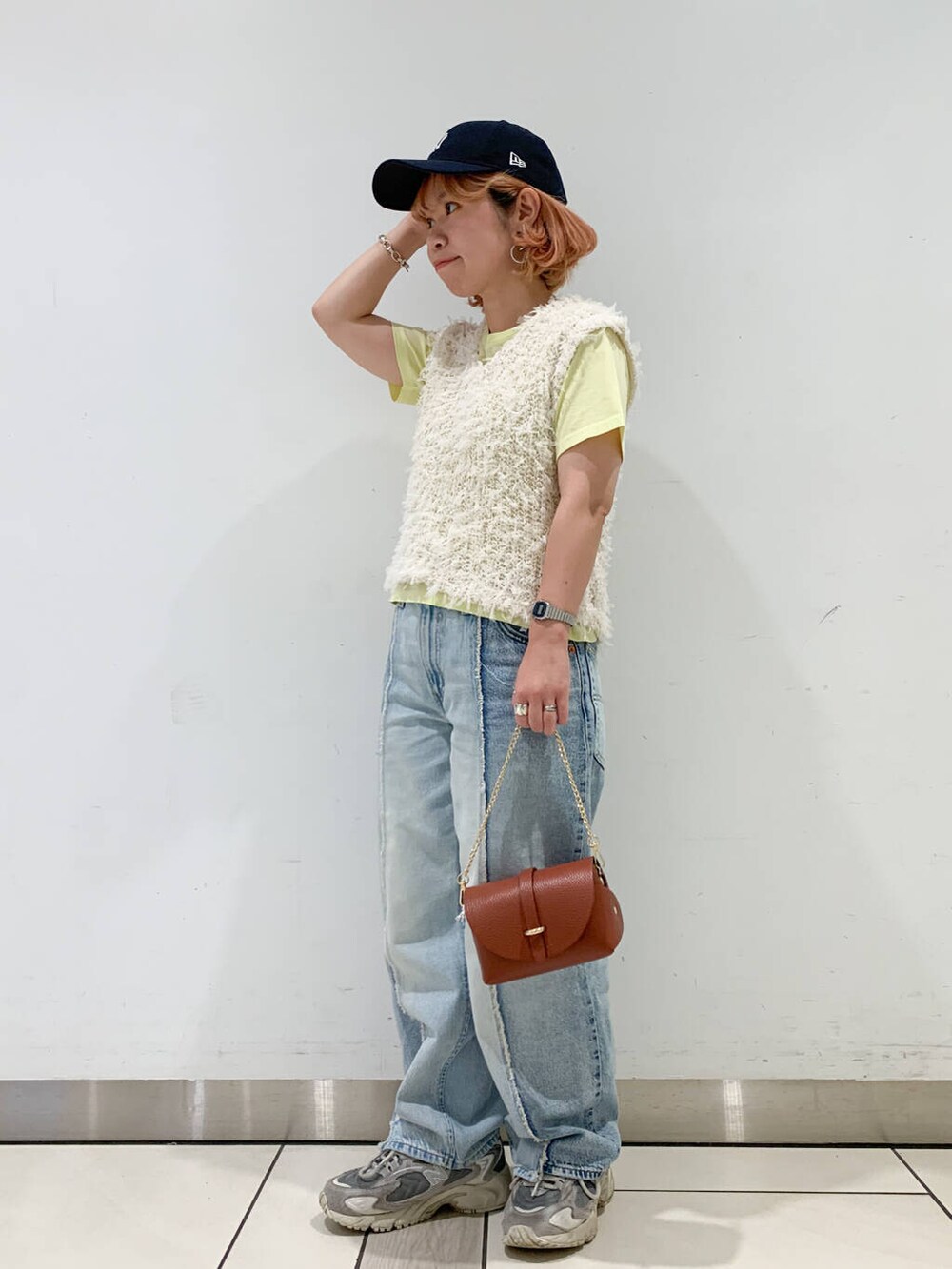 ブラウン系のショルダーバッグ、イエロー系のTシャツ/カットソー、ホワイト系のベストを着用したレディースの夏コーディネートの2枚目の写真