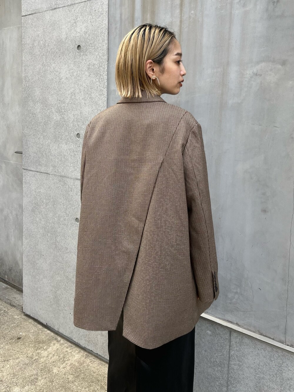 ベージュ系のテーラードジャケット、ゴールド系のTシャツ/カットソー、ブラック系のスカートを着用したレディースの秋コーディネートの4枚目の写真