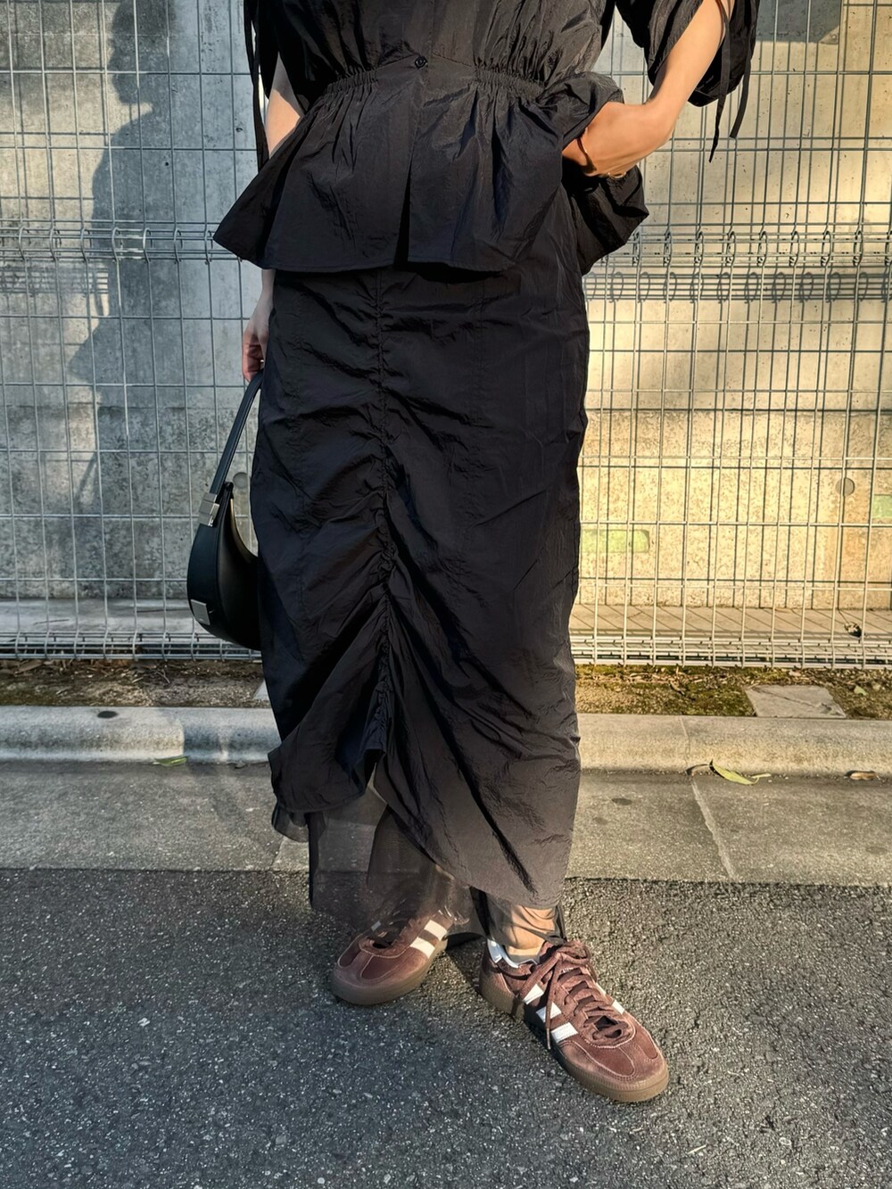 ブラック系のシャツ/ブラウス、ブラック系のスカート、ブラウン系のスニーカーを着用したレディースの春コーディネートの3枚目の写真