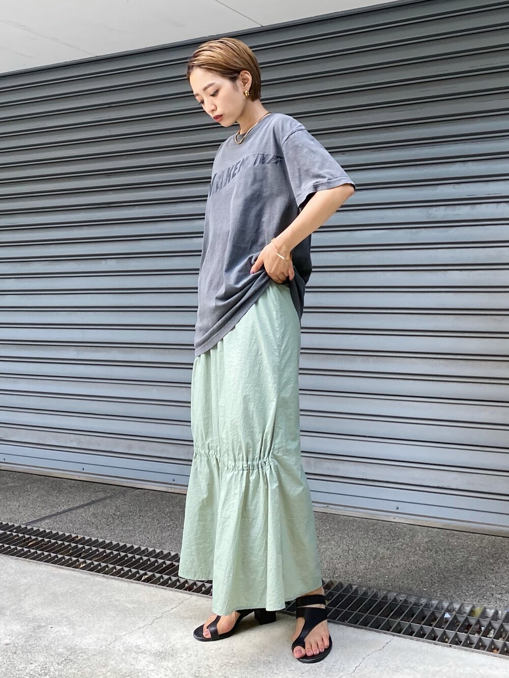 グリーン系のスカート、グレー系のTシャツ/カットソーを着用したレディースの夏コーディネートの2枚目の写真