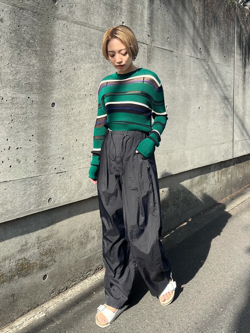 ブラック系のその他パンツ、グリーン系のニット/セーター、ホワイト系のサンダルを着用したレディースの春コーディネートの2枚目の写真