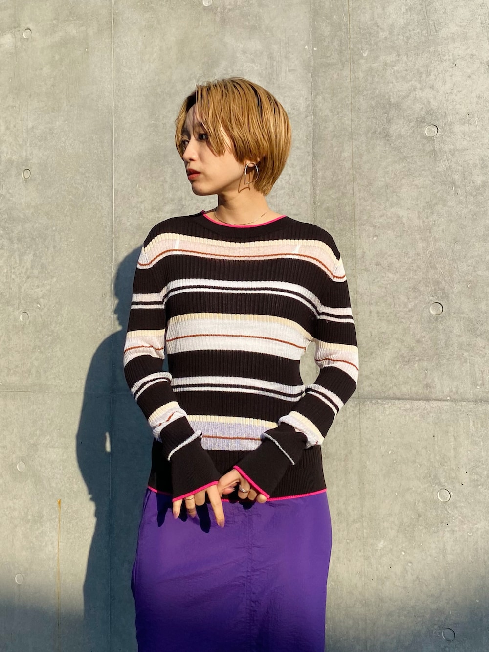 パープル系のスカート、ブラック系のニット/セーター、ブラック系のスニーカーを着用したレディースの冬コーディネートの4枚目の写真