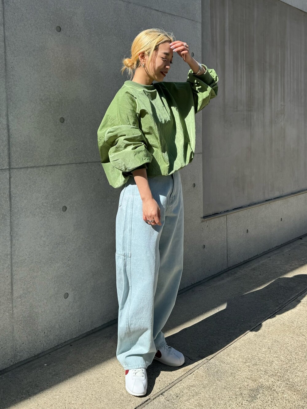 ホワイト系のスニーカー、ブルー系のデニムパンツ、グリーン系のシャツ/ブラウスを着用したレディースの春コーディネートの4枚目の写真