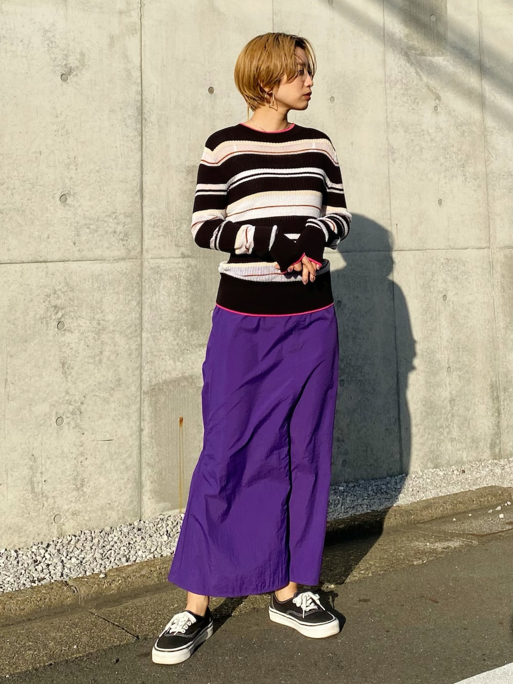 パープル系のスカート、ブラック系のニット/セーター、ブラック系のスニーカーを着用したレディースの冬コーディネートの3枚目の写真