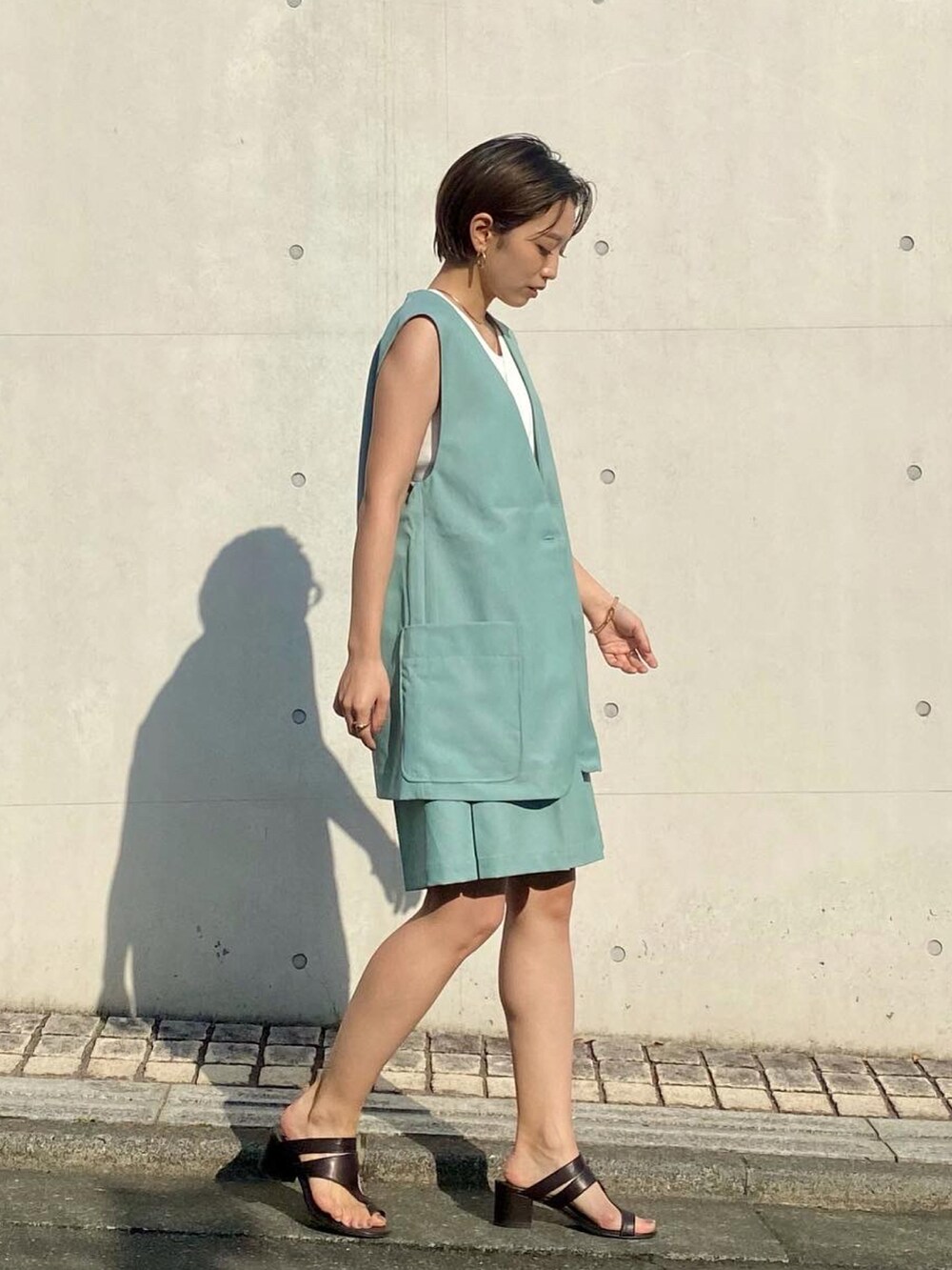 グリーン系のベスト、グリーン系のその他パンツ、ホワイト系のタンクトップを着用したレディースの春コーディネートの2枚目の写真