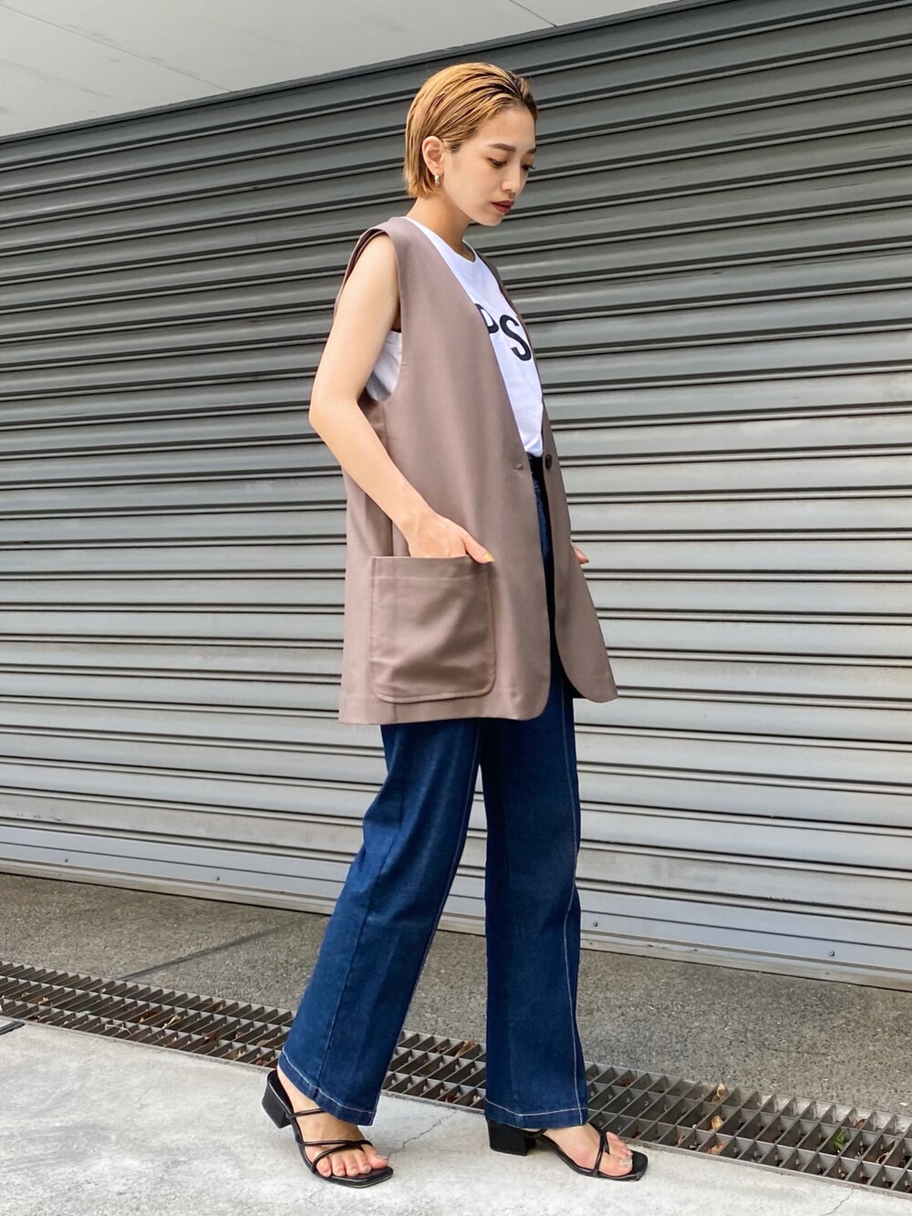 ブルー系のデニムパンツ、ブラウン系のベスト、ホワイト系のタンクトップを着用したレディースの夏コーディネートの2枚目の写真