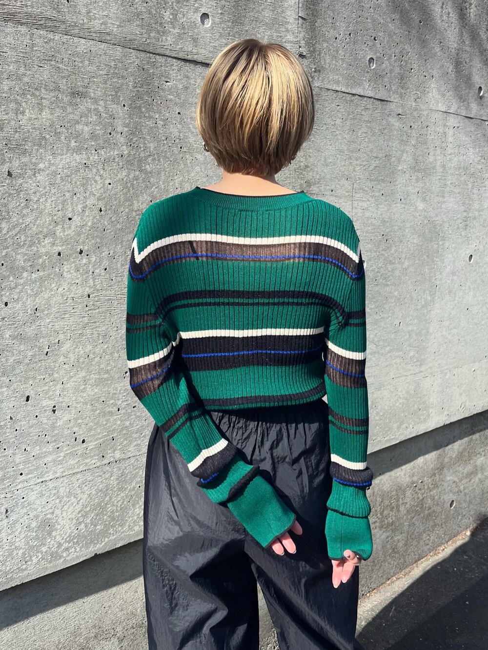 ブラック系のその他パンツ、グリーン系のニット/セーター、ホワイト系のサンダルを着用したレディースの春コーディネートの3枚目の写真