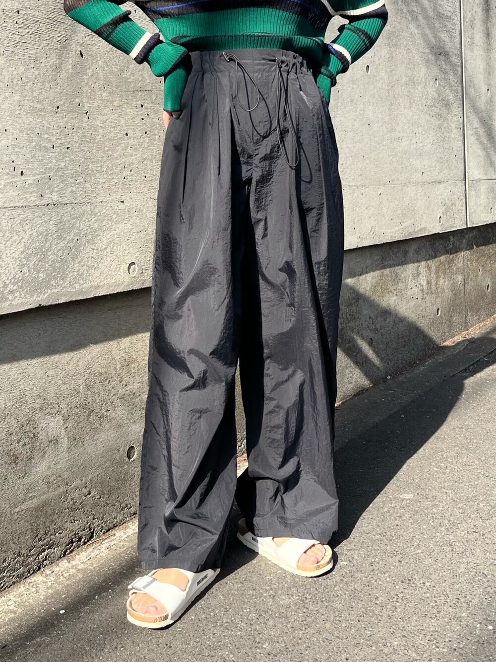 ブラック系のその他パンツ、グリーン系のニット/セーター、ホワイト系のサンダルを着用したレディースの春コーディネートの4枚目の写真