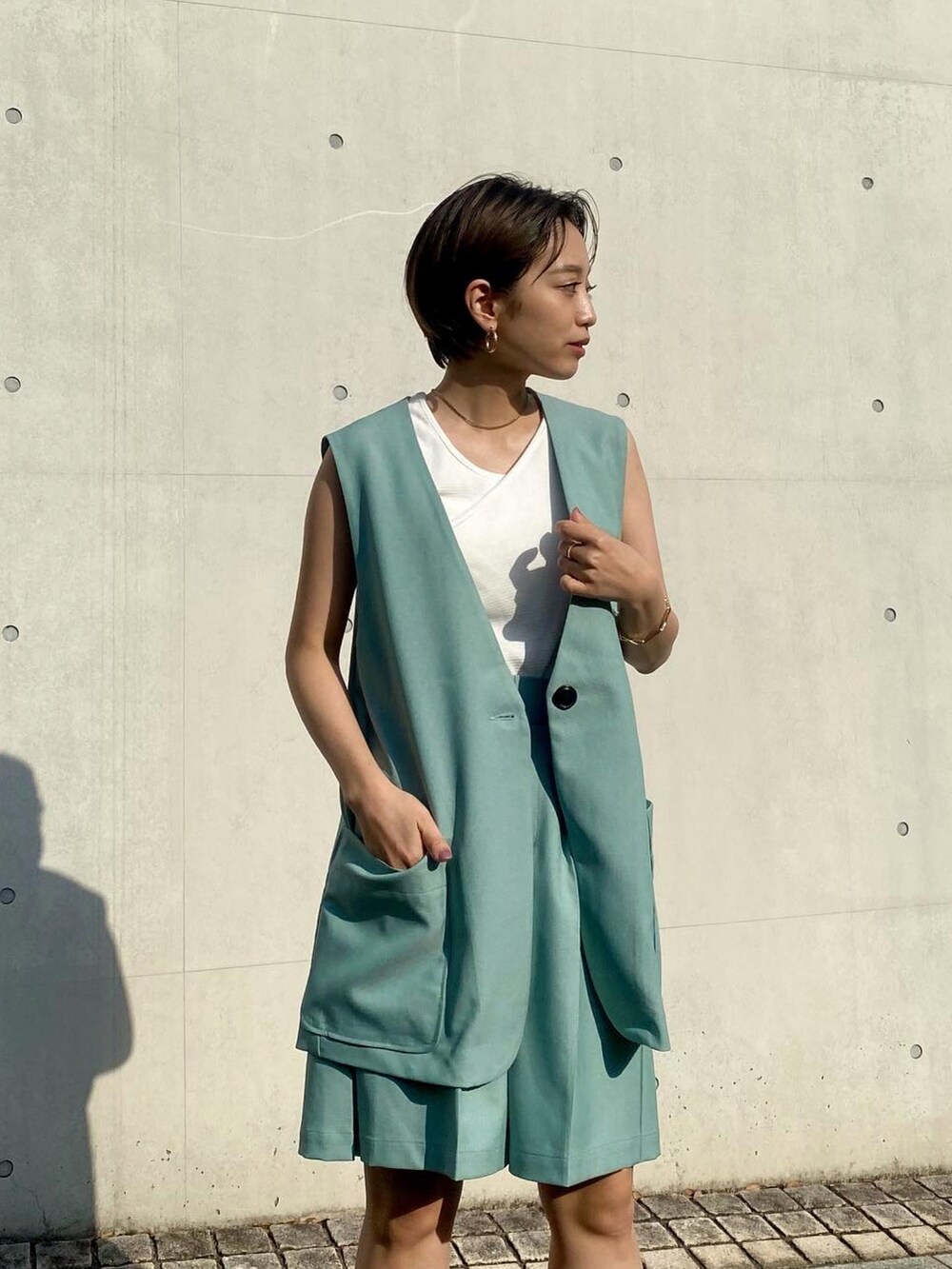 グリーン系のベスト、グリーン系のその他パンツ、ホワイト系のタンクトップを着用したレディースの春コーディネートの3枚目の写真