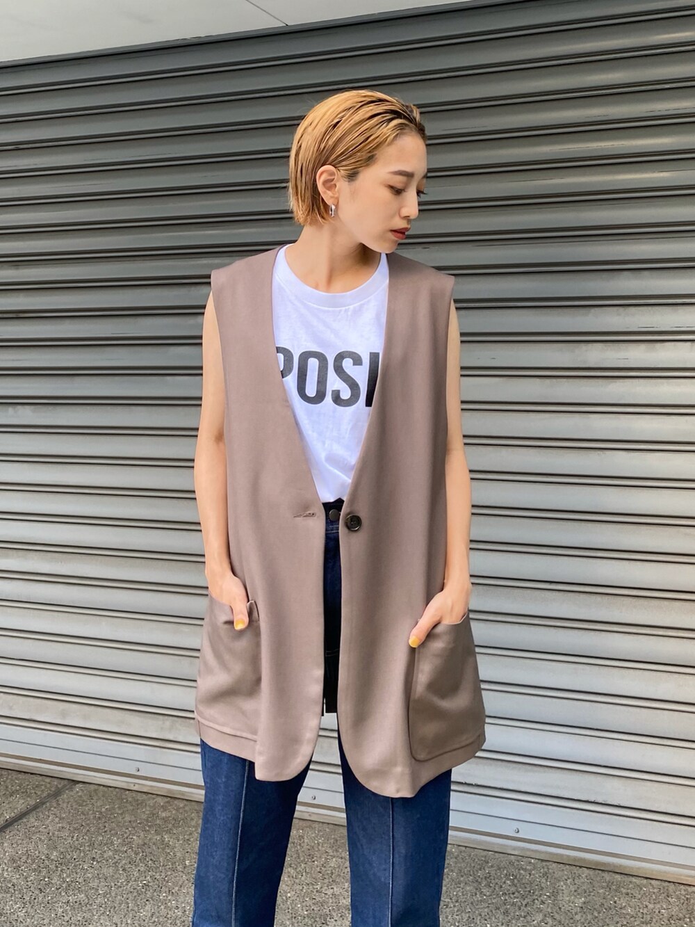 ブルー系のデニムパンツ、ブラウン系のベスト、ホワイト系のタンクトップを着用したレディースの夏コーディネートの3枚目の写真