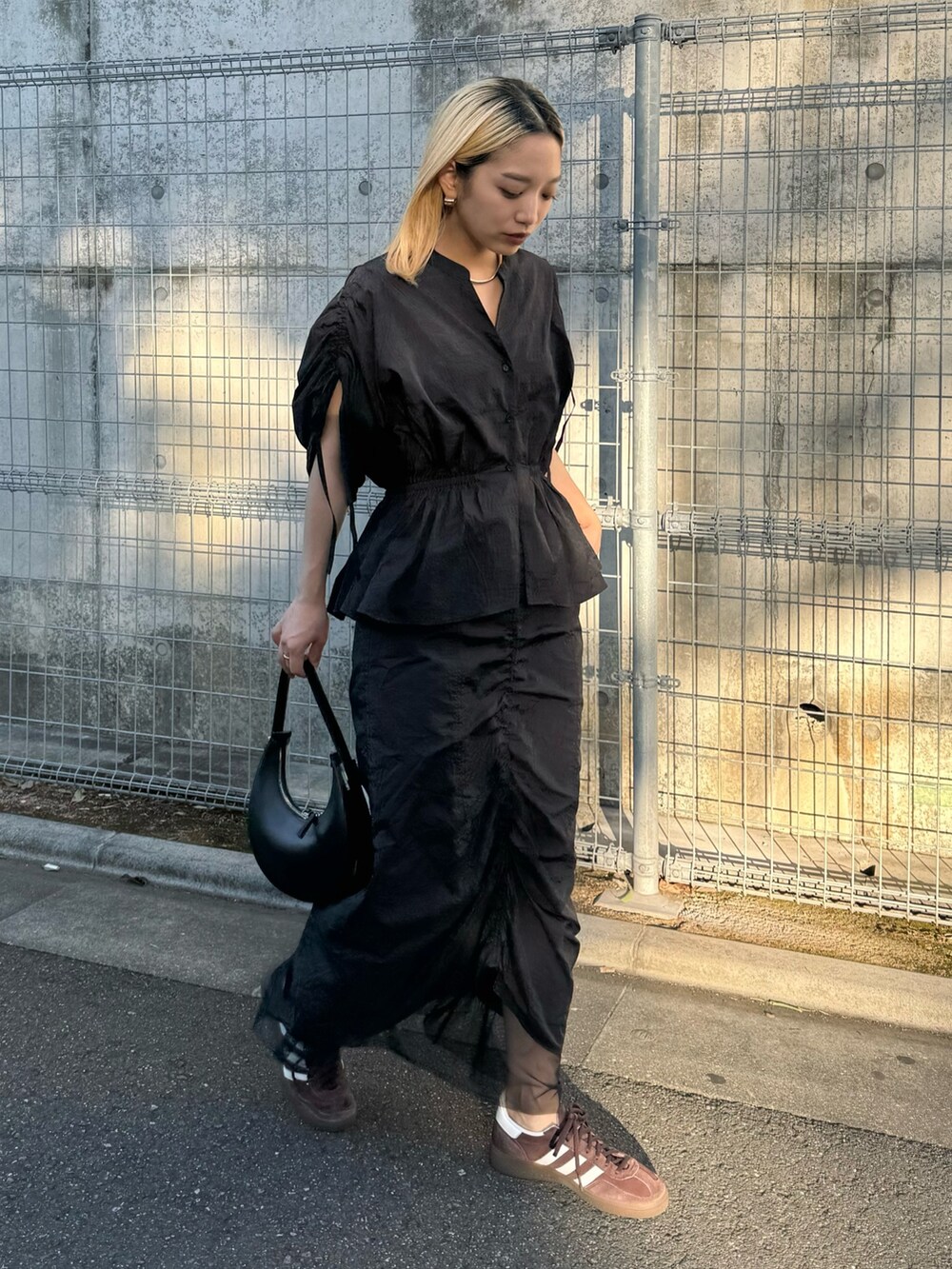 ブラック系のシャツ/ブラウス、ブラック系のスカート、ブラウン系のスニーカーを着用したレディースの春コーディネートの2枚目の写真