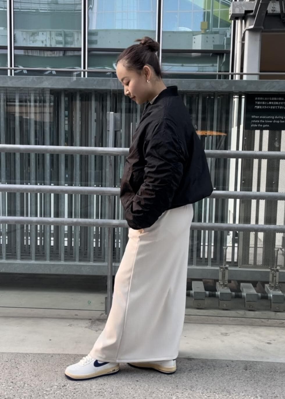 ホワイト系のスニーカー、ホワイト系のスカート、ブラック系のブルゾンを着用したレディースの冬コーディネートの2枚目の写真