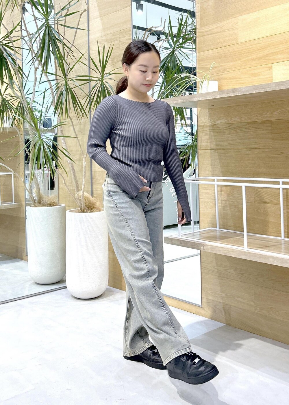 ブラック系のスニーカー、ブラック系のニット/セーター、ベージュ系のデニムパンツを着用したレディースの秋コーディネートの3枚目の写真