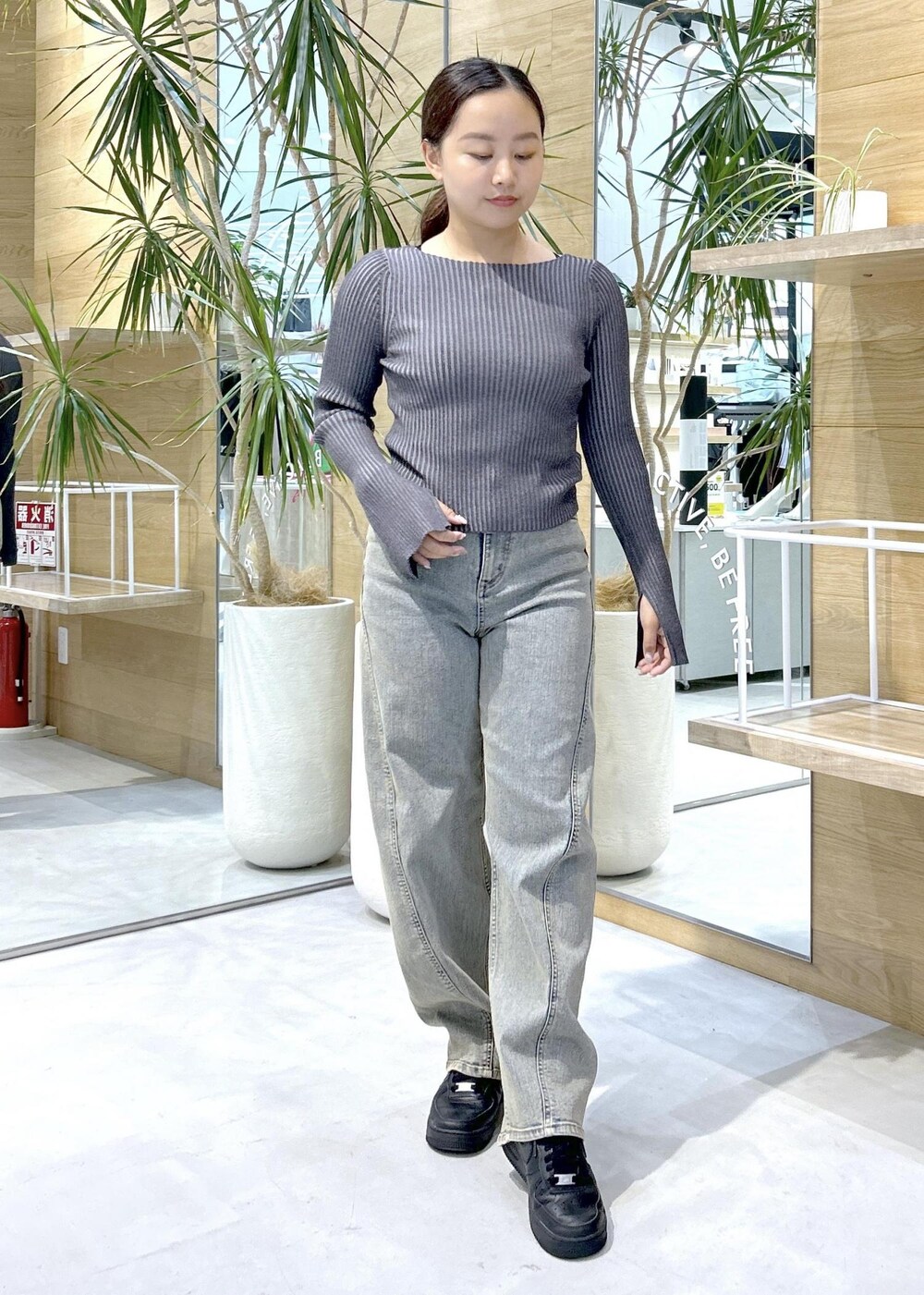 ブラック系のスニーカー、ブラック系のニット/セーター、ベージュ系のデニムパンツを着用したレディースの秋コーディネートの2枚目の写真