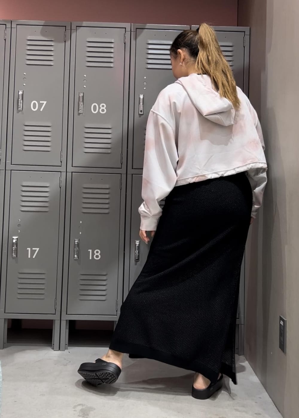 ブラック系のサンダル、ホワイト系のパーカー、ブラック系のスカートを着用したレディースの春コーディネートの3枚目の写真