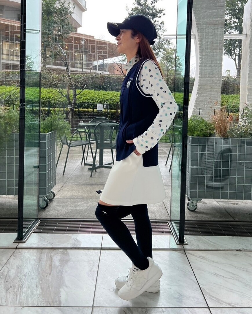 グリーン系のTシャツ/カットソー、ブルー系のベスト、ホワイト系のスカートを着用したレディースの冬コーディネートの2枚目の写真