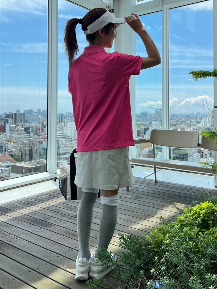 ピンク系のポロシャツ、ベージュ系のスカート、ホワイト系のトートバッグを着用したレディースの夏コーディネートの3枚目の写真