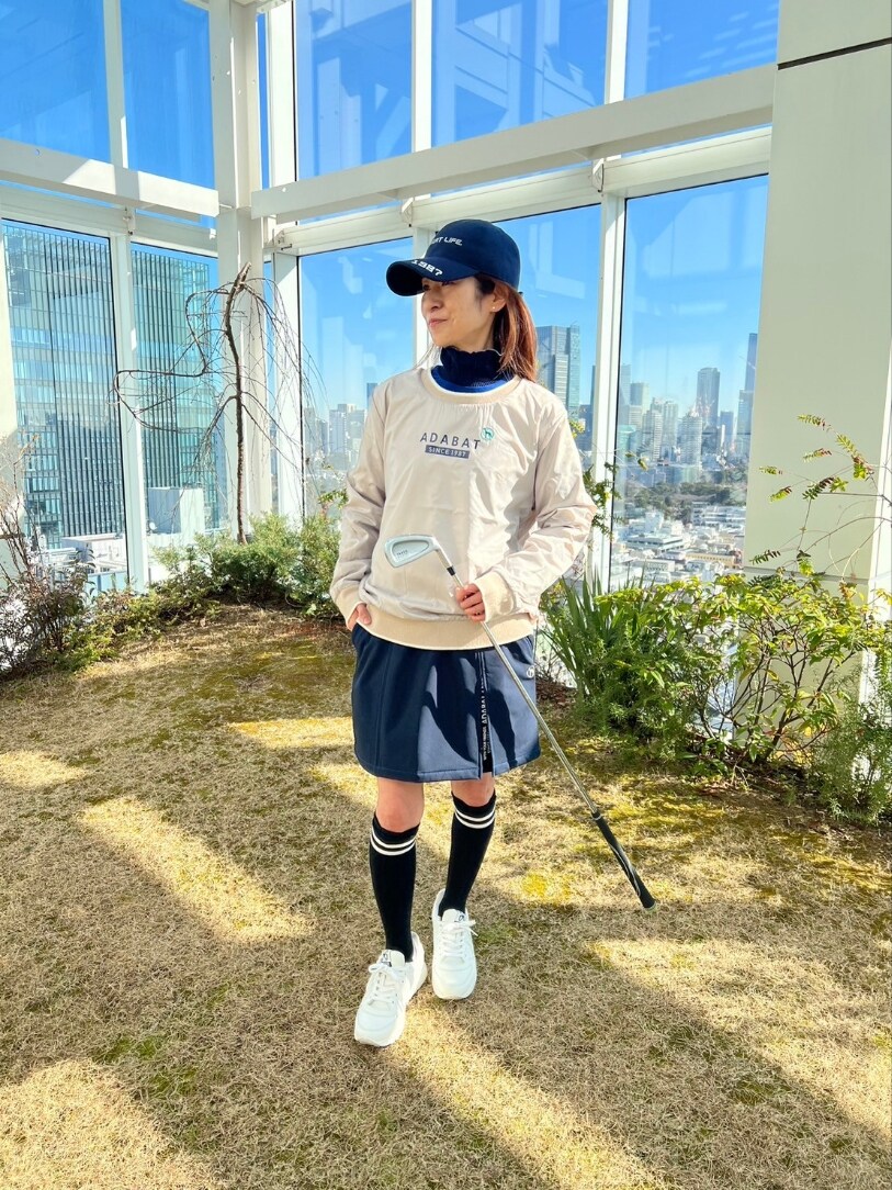 ホワイト系のニット/セーター、ブルー系のスカート、ブルー系のゴルフグッズを着用したレディースの冬コーディネートの3枚目の写真