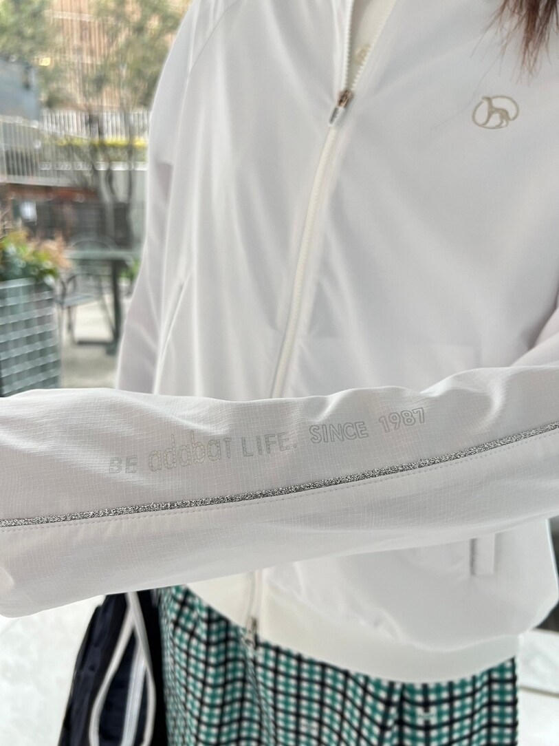 ホワイト系のブルゾン、ホワイト系のスカート、ブルー系のトートバッグを着用したレディースの春コーディネートの4枚目の写真