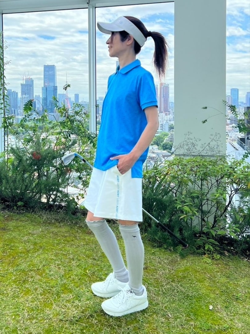 ブルー系のポロシャツ、ホワイト系のその他パンツ、ホワイト系のサンバイザーを着用したレディースの春コーディネートの2枚目の写真