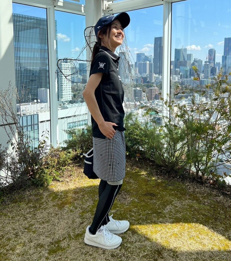 ブラック系のポロシャツ、ブルー系のハンドバッグ、ブルー系のスカートを着用したレディースの春コーディネートの3枚目の写真