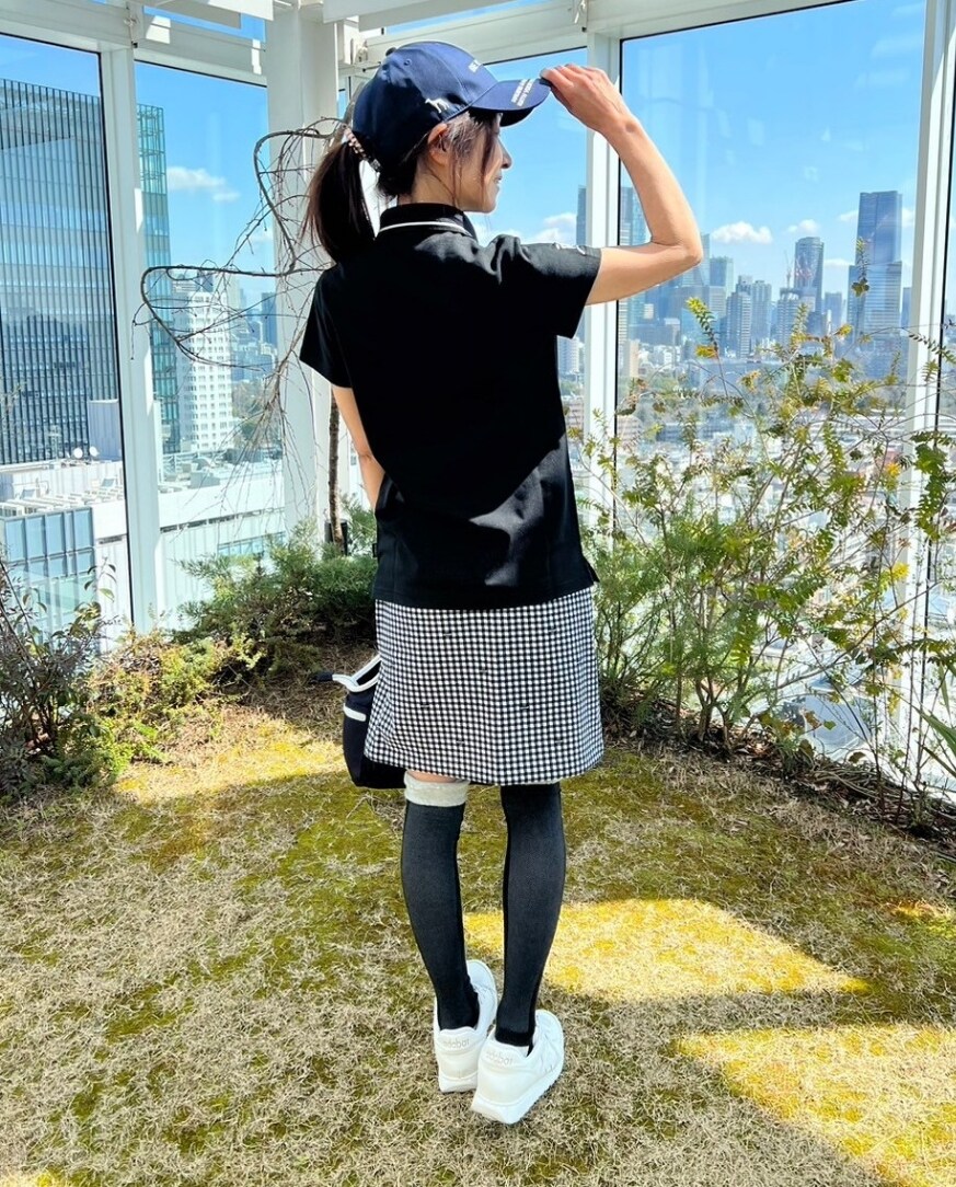 ブラック系のポロシャツ、ブルー系のハンドバッグ、ブルー系のスカートを着用したレディースの春コーディネートの4枚目の写真