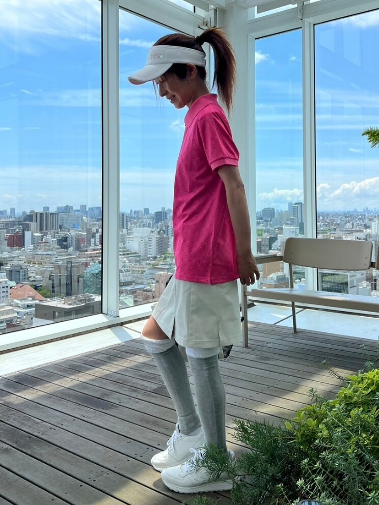 ピンク系のポロシャツ、ベージュ系のスカート、ホワイト系のトートバッグを着用したレディースの夏コーディネートの2枚目の写真