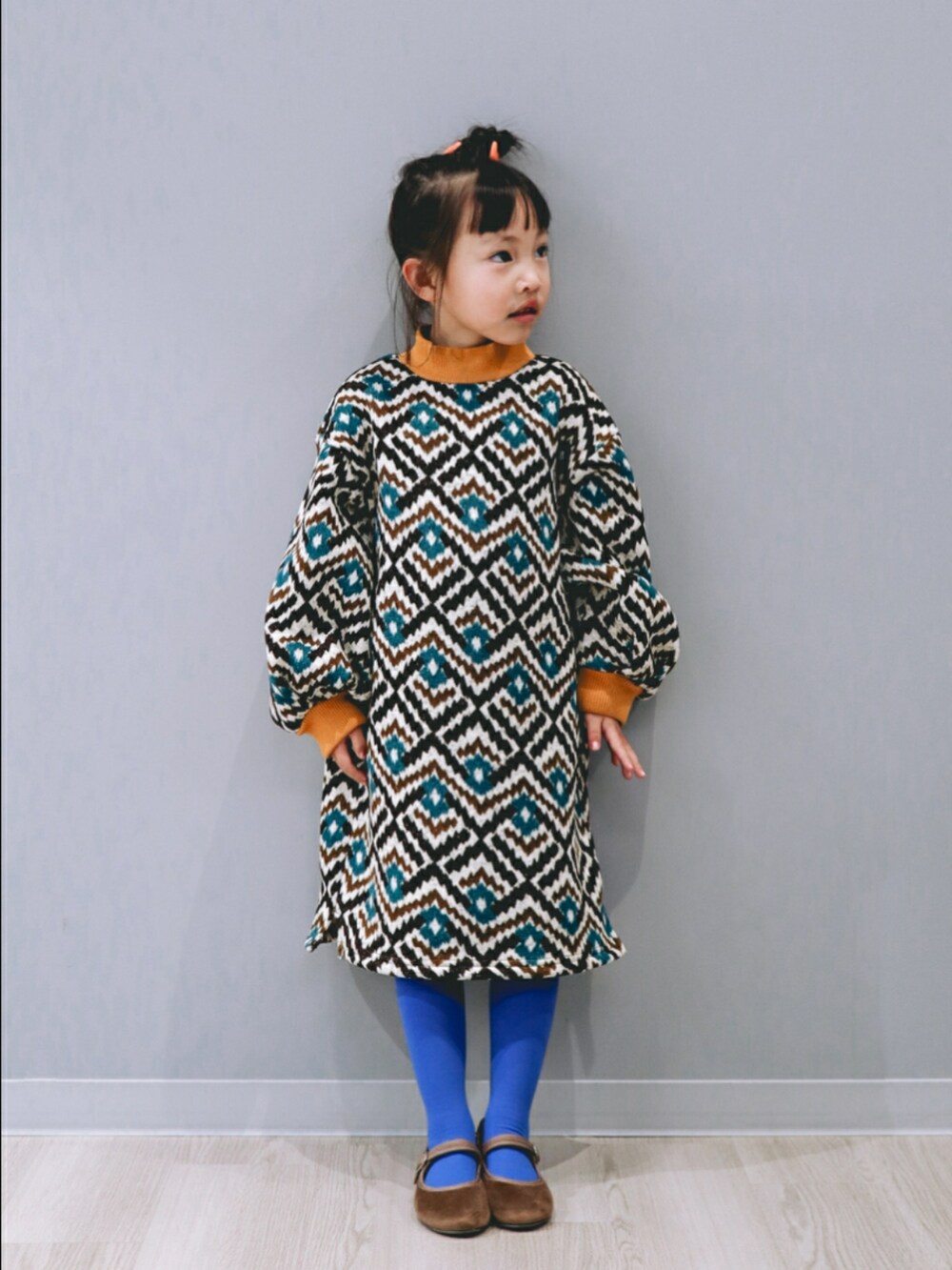 ブラウン系のワンピース、ブラウン系のバレエシューズ、ブルー系のタイツ/ストッキングを着用したキッズの冬コーディネートの2枚目の写真