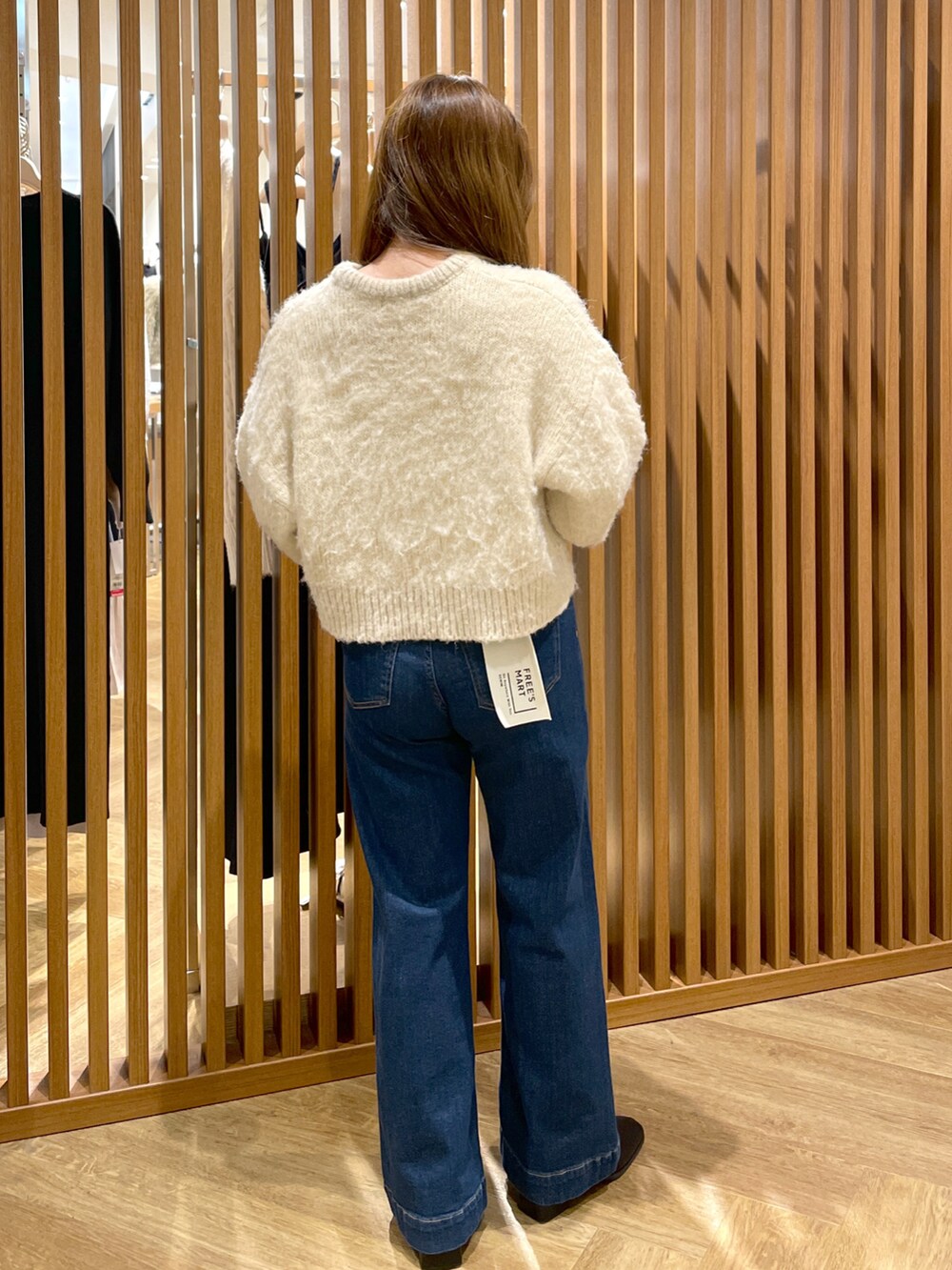 ベージュ系のニット/セーター、シルバー系のハンドバッグ、ブルー系のデニムパンツを着用したレディースの冬コーディネートの2枚目の写真