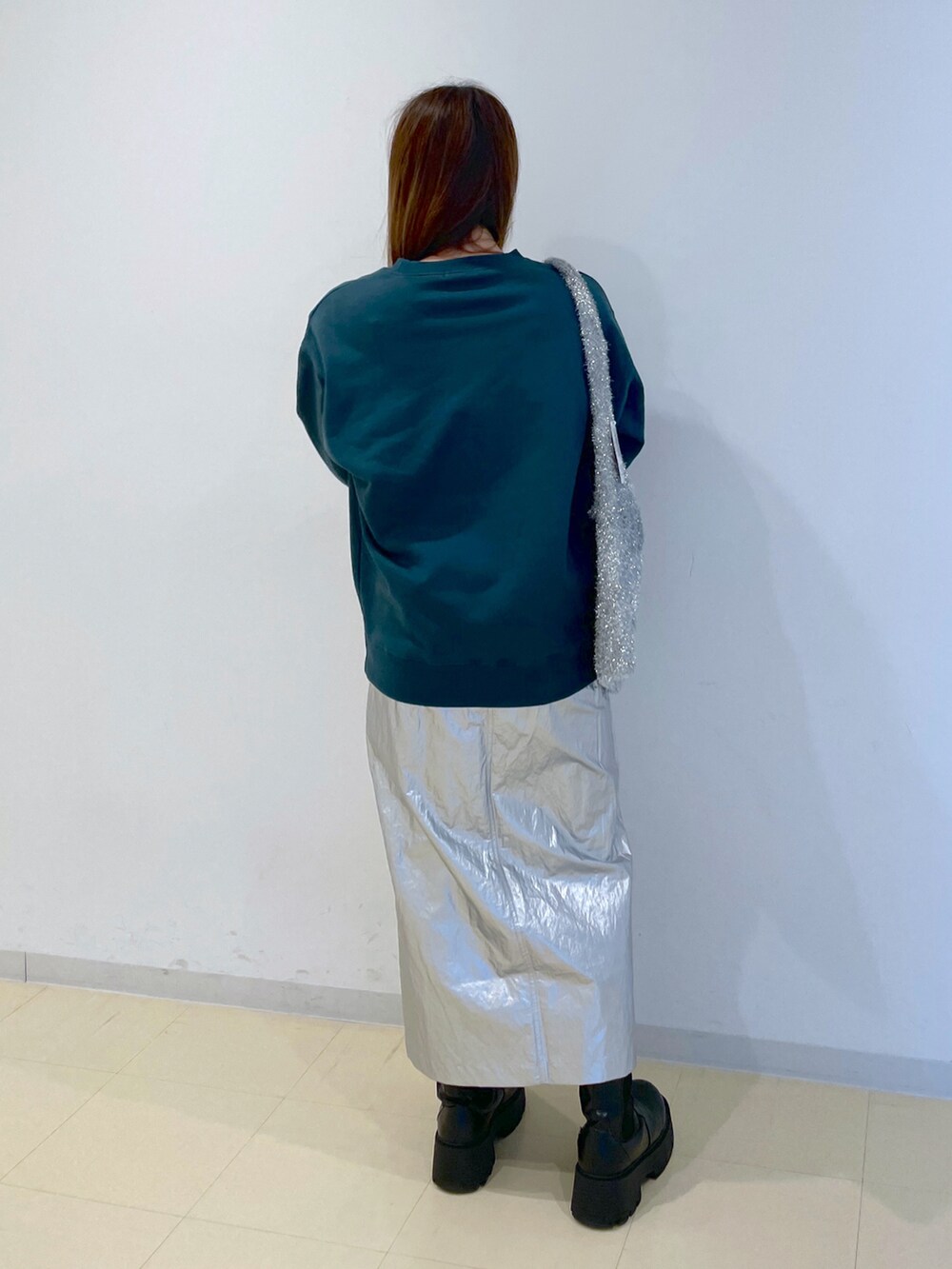 グリーン系のTシャツ/カットソー、シルバー系のスカート、シルバー系のトートバッグを着用したレディースの冬コーディネートの2枚目の写真