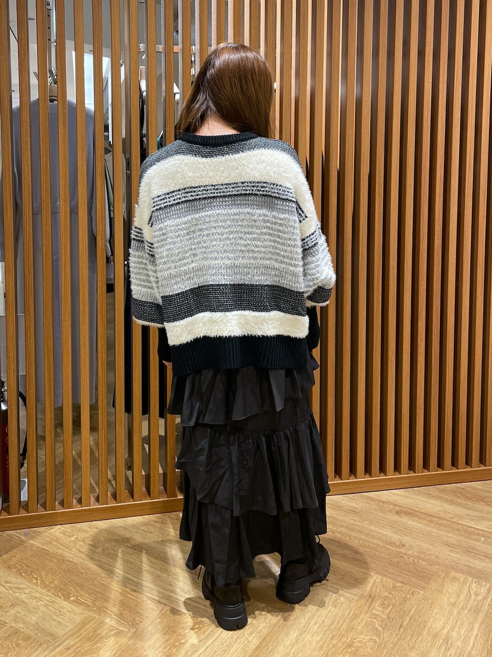 ブラック系のスカート、ブラック系のニット/セーター、ブラック系のブーツを着用したレディースの冬コーディネートの2枚目の写真