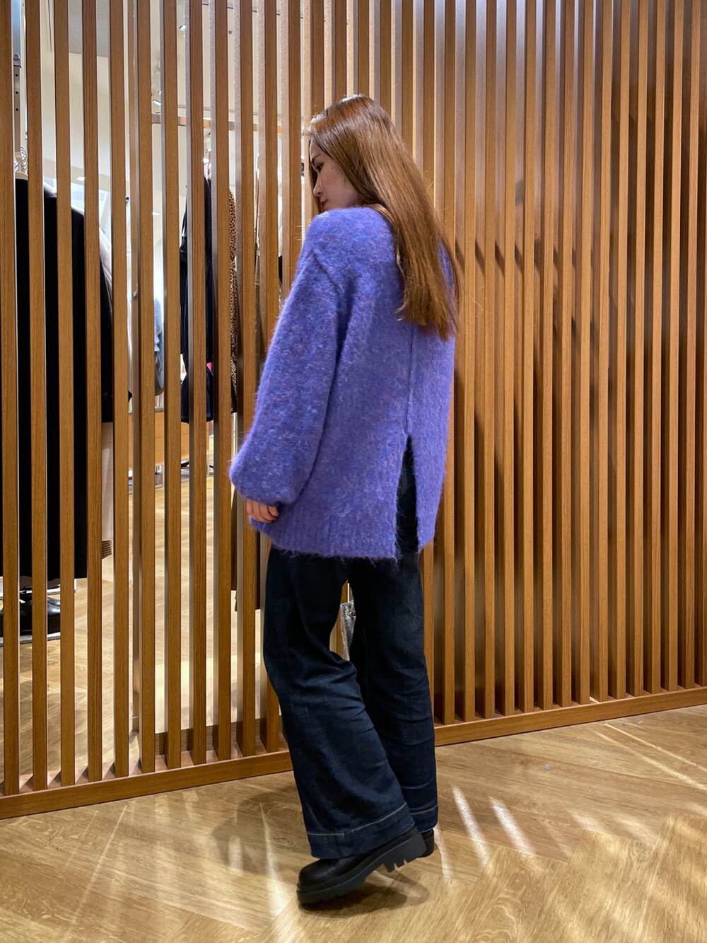 ブルー系のニット/セーター、シルバー系のハンドバッグ、ブルー系のデニムパンツを着用したレディースの冬コーディネートの2枚目の写真