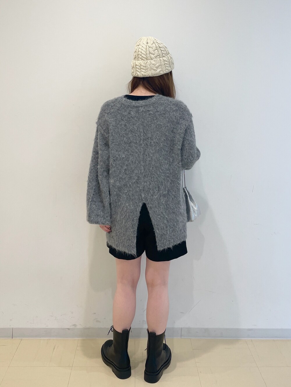 ベージュ系のニット/セーター、シルバー系のハンドバッグ、ブラック系のブーツを着用したレディースの冬コーディネートの3枚目の写真