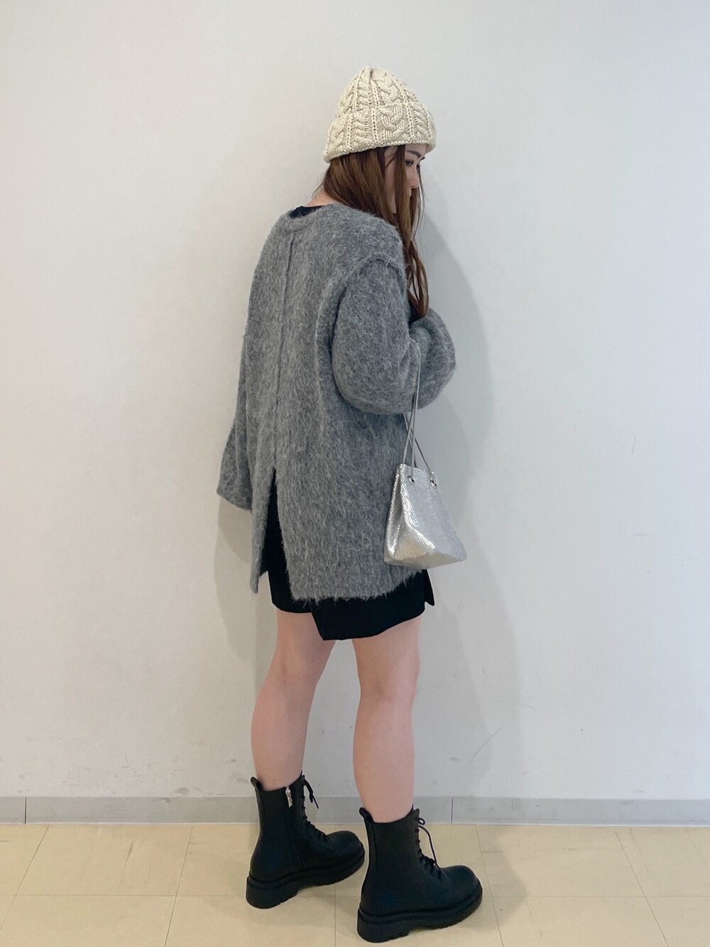 ベージュ系のニット/セーター、シルバー系のハンドバッグ、ブラック系のブーツを着用したレディースの冬コーディネートの2枚目の写真