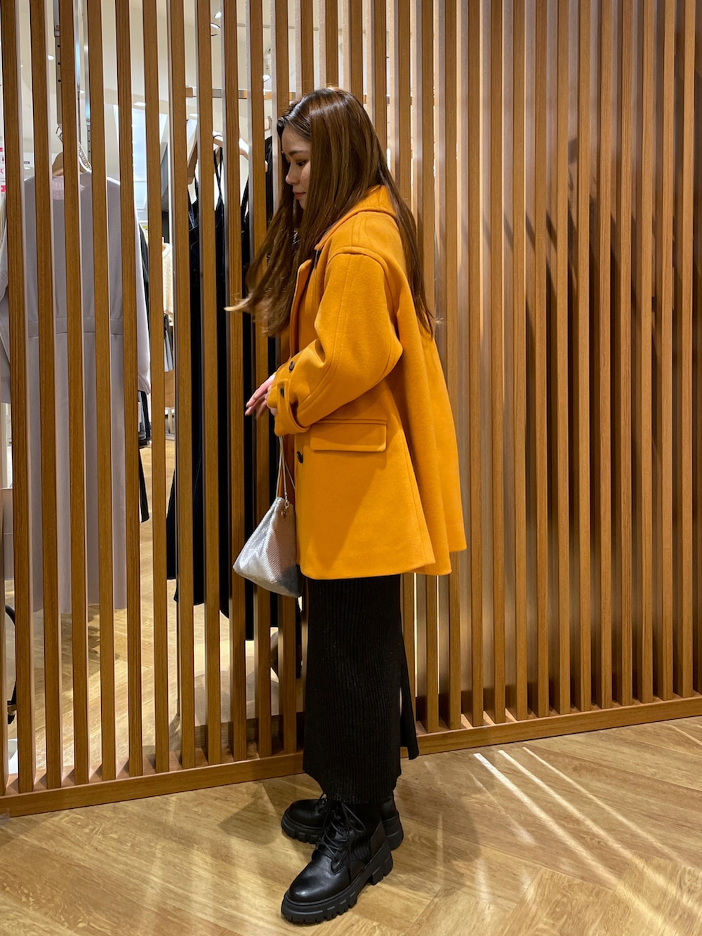 ホワイト系のニット/セーター、ブラック系のスカート、オレンジ系のピーコートを着用したレディースの冬コーディネートの2枚目の写真