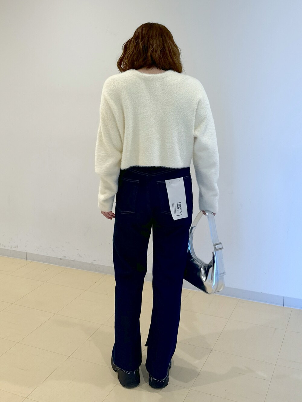 ホワイト系のニット/セーター、ブルー系のデニムパンツ、シルバー系のショルダーバッグを着用したレディースの冬コーディネートの2枚目の写真