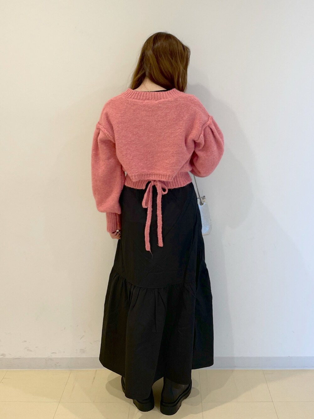 ピンク系のニット/セーター、シルバー系のハンドバッグ、ブラック系のスカートを着用したレディースの冬コーディネートの3枚目の写真