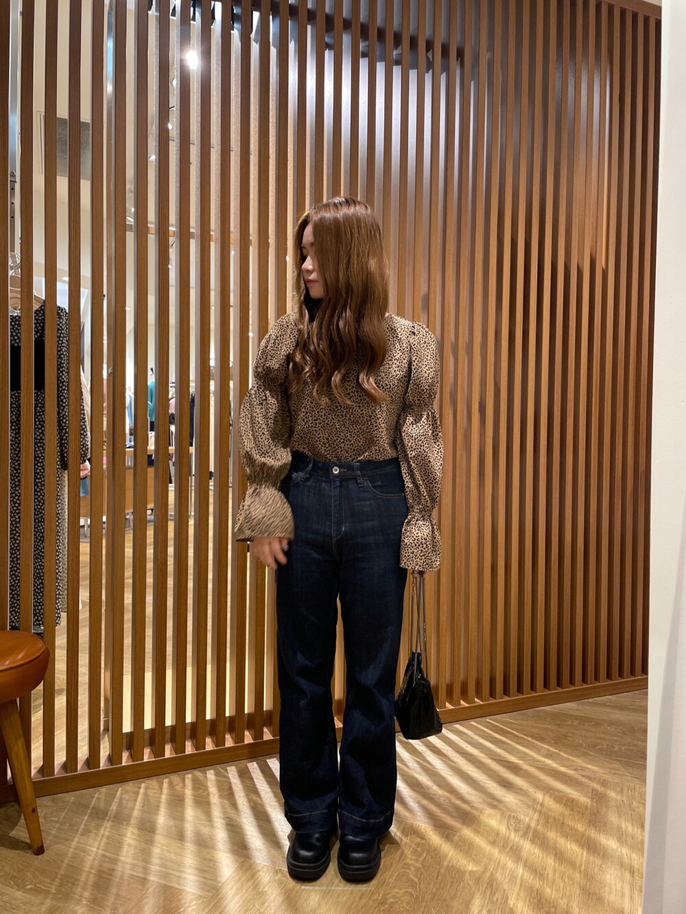 ベージュ系のシャツ/ブラウス、ブルー系のデニムパンツ、ブラック系のハンドバッグを着用したレディースの秋コーディネートの2枚目の写真