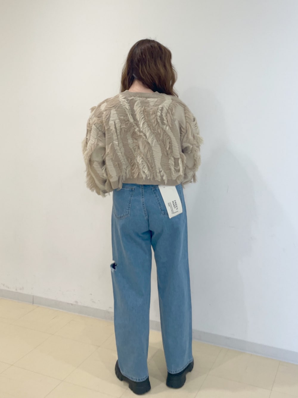 ベージュ系のニット/セーター、ブルー系のデニムパンツ、シルバー系のハンドバッグを着用したレディースの冬コーディネートの2枚目の写真